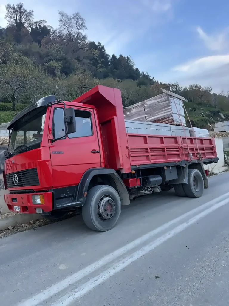 Κόκκινο ανατρεπόμενο φορτηγό φορτωμένο με οικοδομικά υλικά